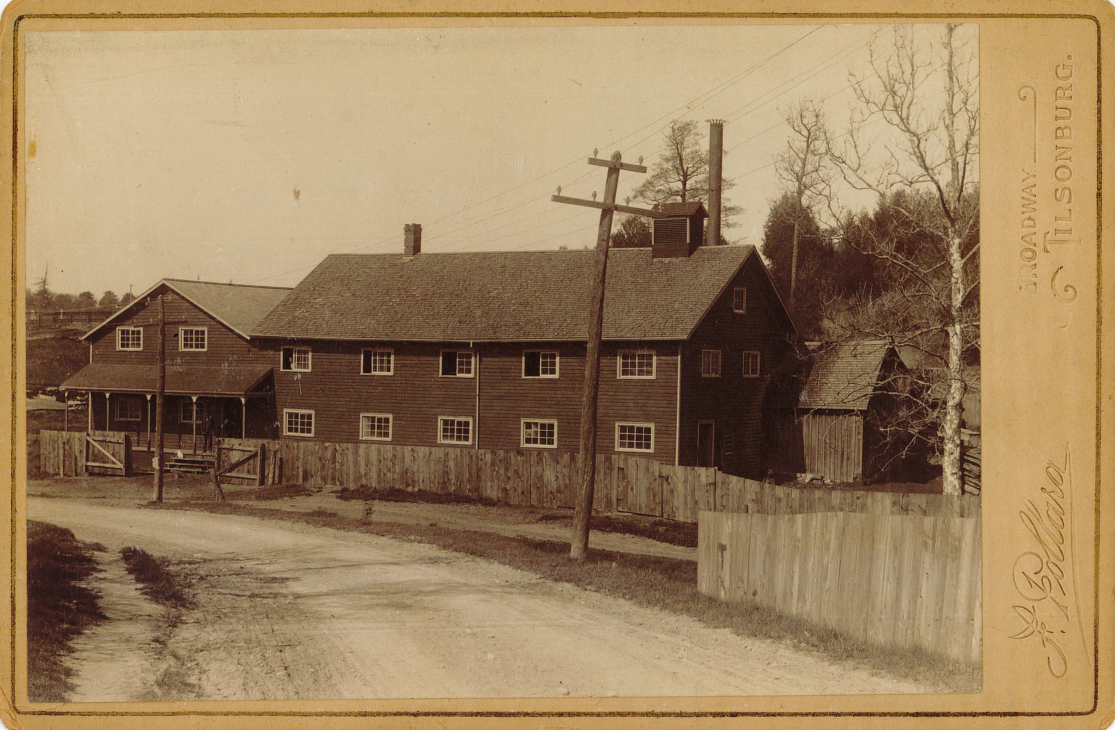 A photograph of a two-storey wooden frame building surrounded by a fence.