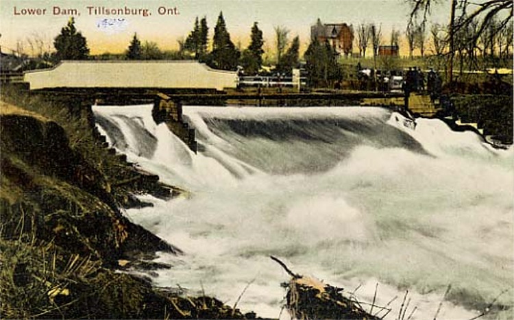 A postcard with an image of the lower dam in Tillsonburg. Water is rushing quickly over the dam.